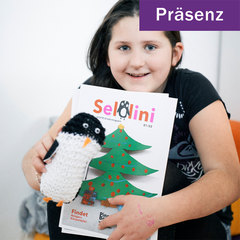 Junges Mädchen hält eine Sellini Kinderzeitschrift und ein Pinguin-Maskottchen